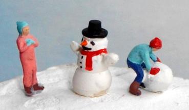Kinder bauen einen Schneemann